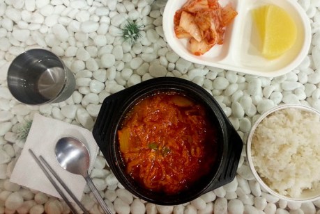 Kimchi jjigae, accompanied by more kimchi, pickled radish, and white rice.